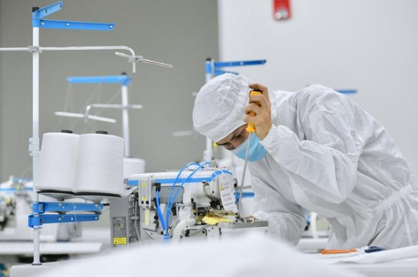 在位于晉江的福建海峽石墨烯產業技術研究院的無菌實驗室，技術人員在調試剛剛送達的防護服生產設備。新華社記者姜克紅攝
